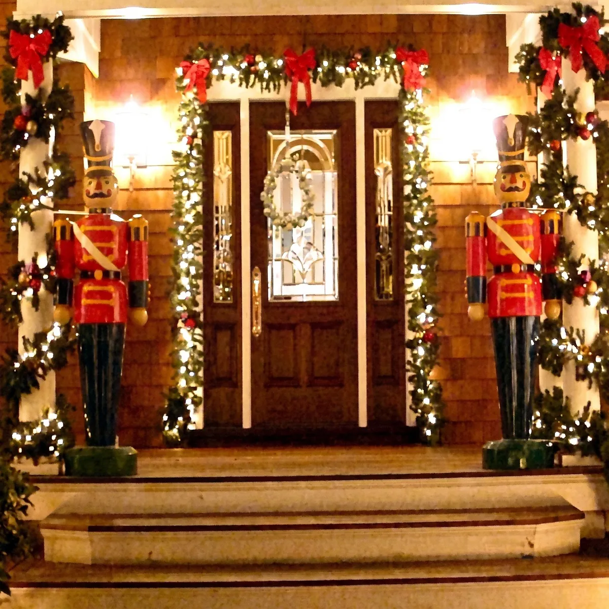 Front door framed in lit garland with two life-size nutcracker soldiers